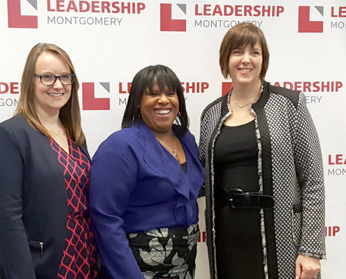 3 woman smiling in front of a Leadership Montgomery backdrop
