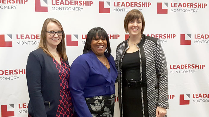 3 woman smiling in front of a Leadership Montgomery backdrop