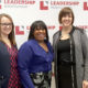 3 woman smiling in front of a Leadership Montgomery backdrop