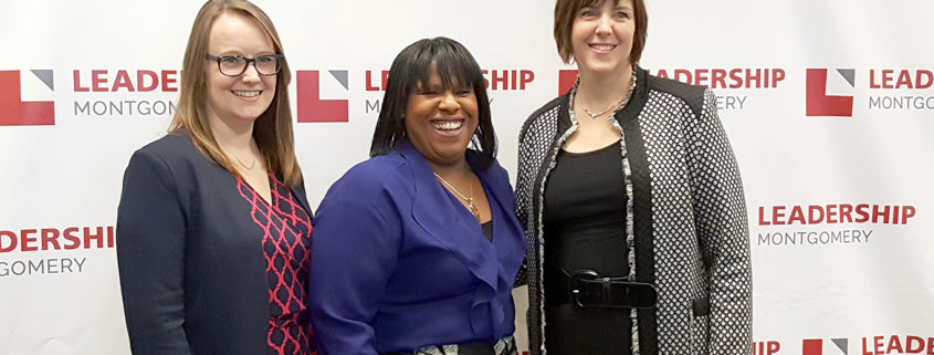 3 woman smiling in front of a Leadership Montgomery backdrop