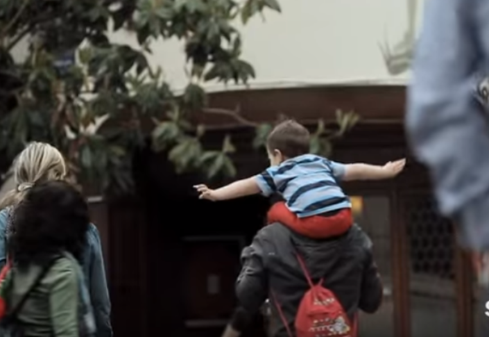 a kid with their arms out on their parents shoulders