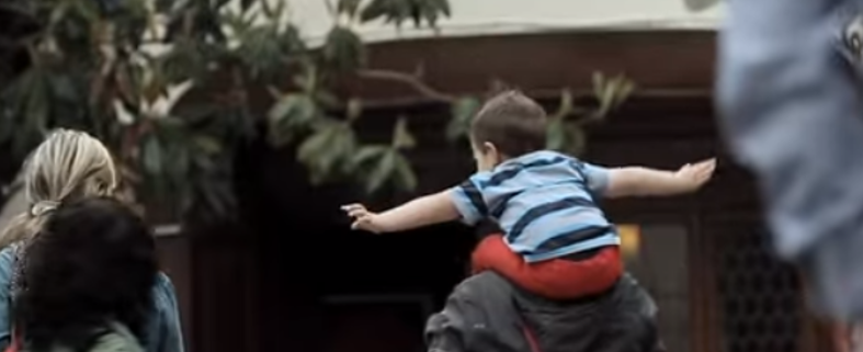 a kid with their arms out on their parents shoulders