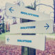 A sign post with signs pointing in multiple direction that all say SOLUTION