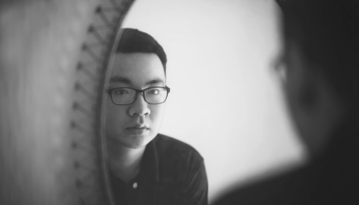 the reflection of a young man with glasses in a mirror