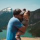 adult holding a child and giving them a hug in front of a picturesque mountain landscape