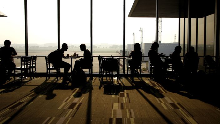 People talking in small groups silhouetted against a large window
