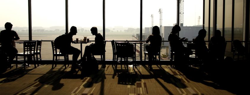 People talking in small groups silhouetted against a large window