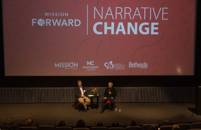 A wide view of a stage with two men in chairs