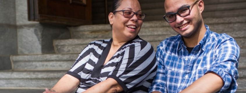 A mother and son sit on the front steps of a building together