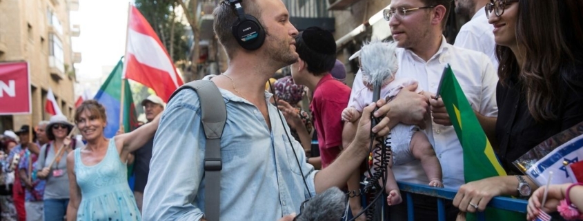 A reporter holds a microphone while talking with a member of the crowd