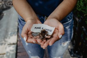 a woman's hand holding coins with a scrape paper reading "Make A Change"