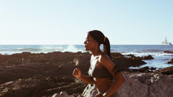 Woman in workout clothes running by the beach