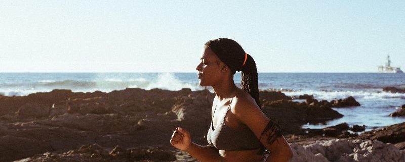 Woman in workout clothes running by the beach