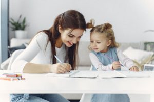 Mom and young daughter writing together