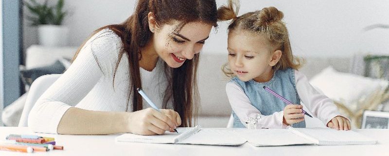 Mom and young daughter writing together