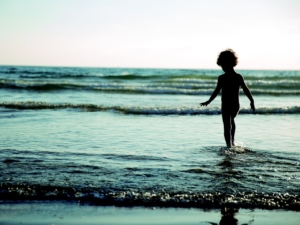 child walking into the waves on the beach