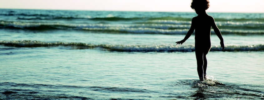 child walking into the waves on the beach