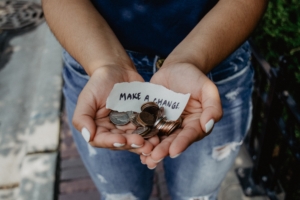 Cupped hands holding coins and paper that reads Make A Change