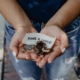 Cupped hands holding coins and paper that reads Make A Change
