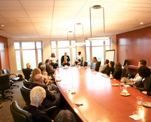 A group of professionals around a conference table listening to a presentation