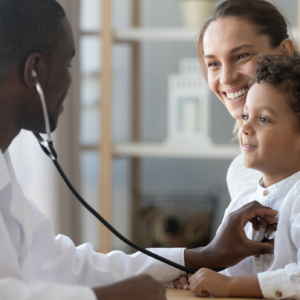 Black doctor using a stethoscope on a young boy sitting in mother's lap