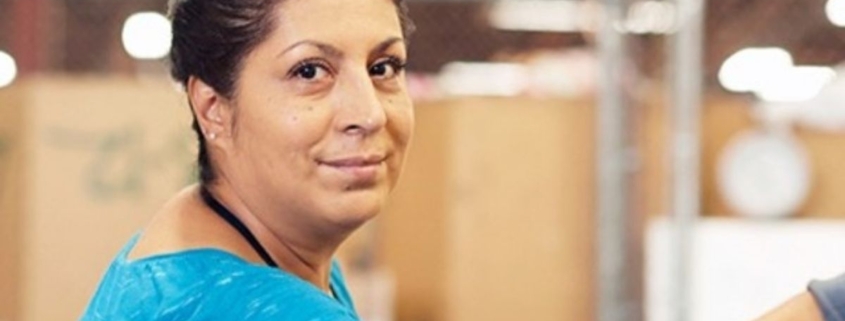 woman smiling at camera, working in manufacturing center