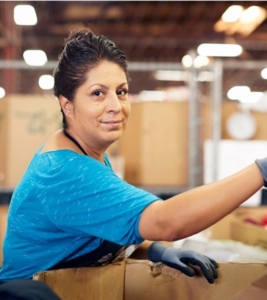 woman smiling at camera, working in manufacturing center