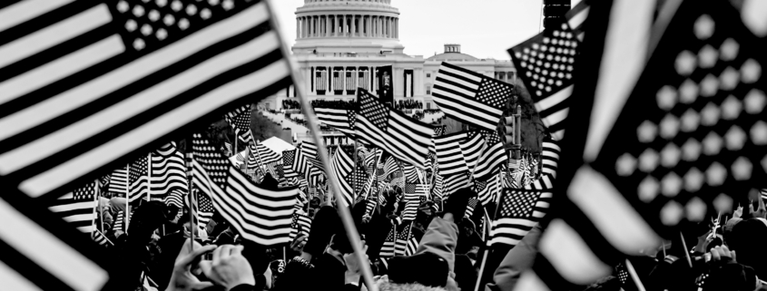 Rally of people in Washington DC with American Flags. The Capital Building is in the distance