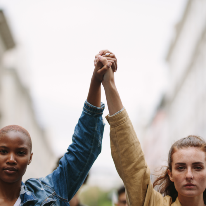 Group of activists with holding hands protesting in the city. Rebellions doing demonstration on the street holding hands.