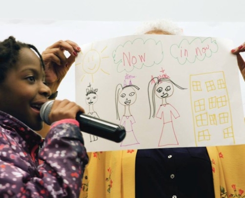 Female with a microphone holding up a drawing