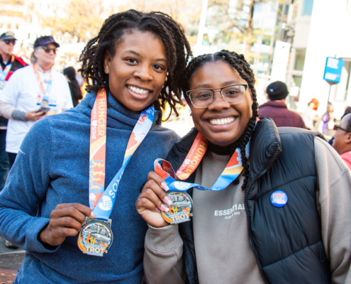 Two runners holding up the medals from the SOME Trot for Hunger around their neck