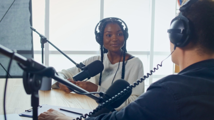 Female Host Talking to a Guest Friend on a Podcast Radio Station in the Studio.