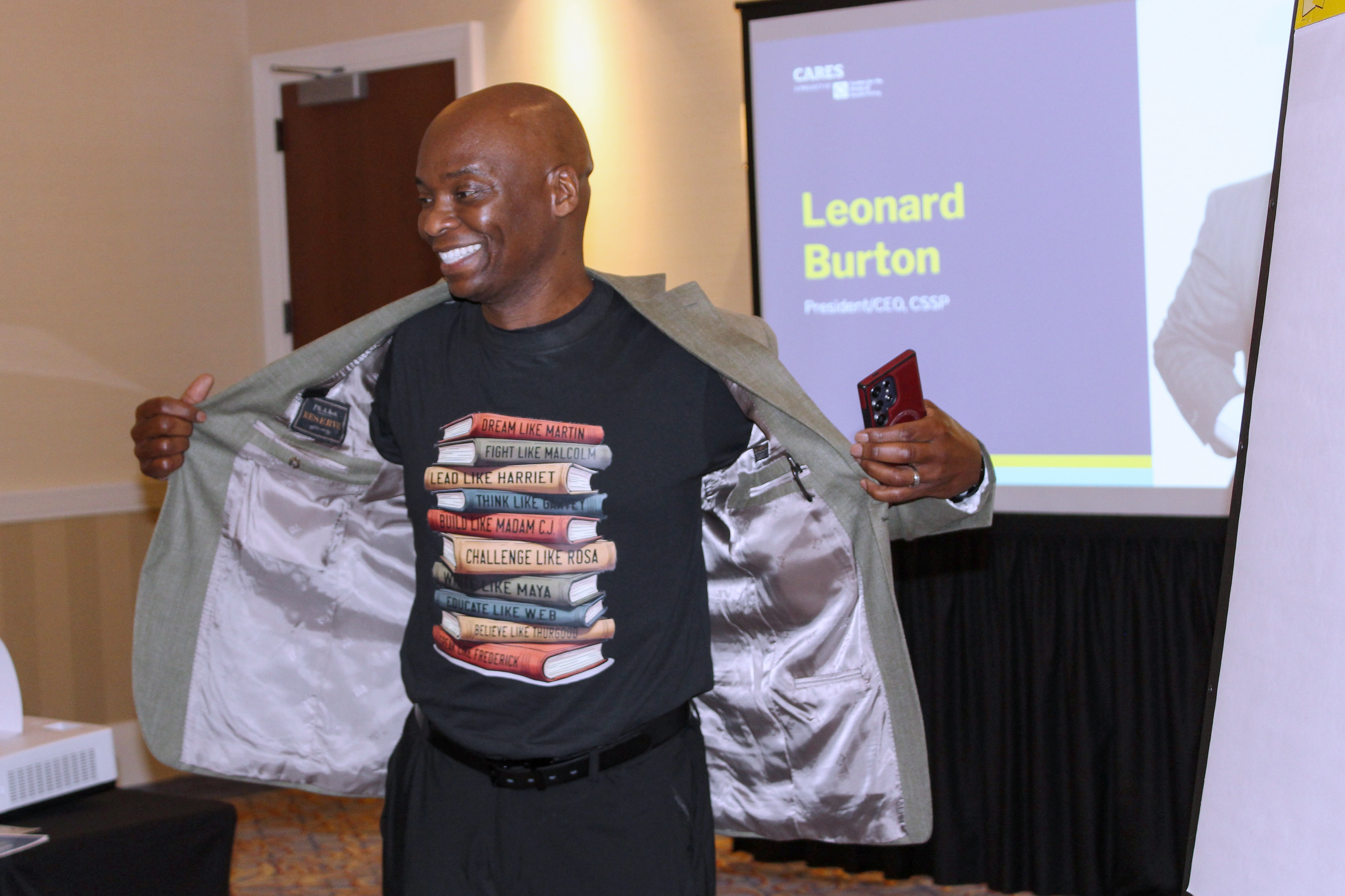 Leanord Burton of CSSP smiling and showing the book images on his shirt while speaking at CARES conference.
