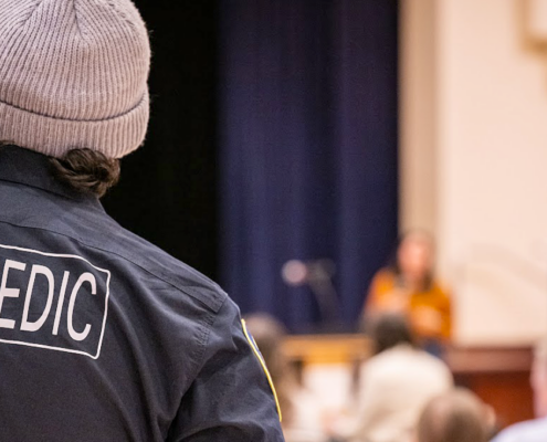 Paramedic watching and listening to a speaker at an event.